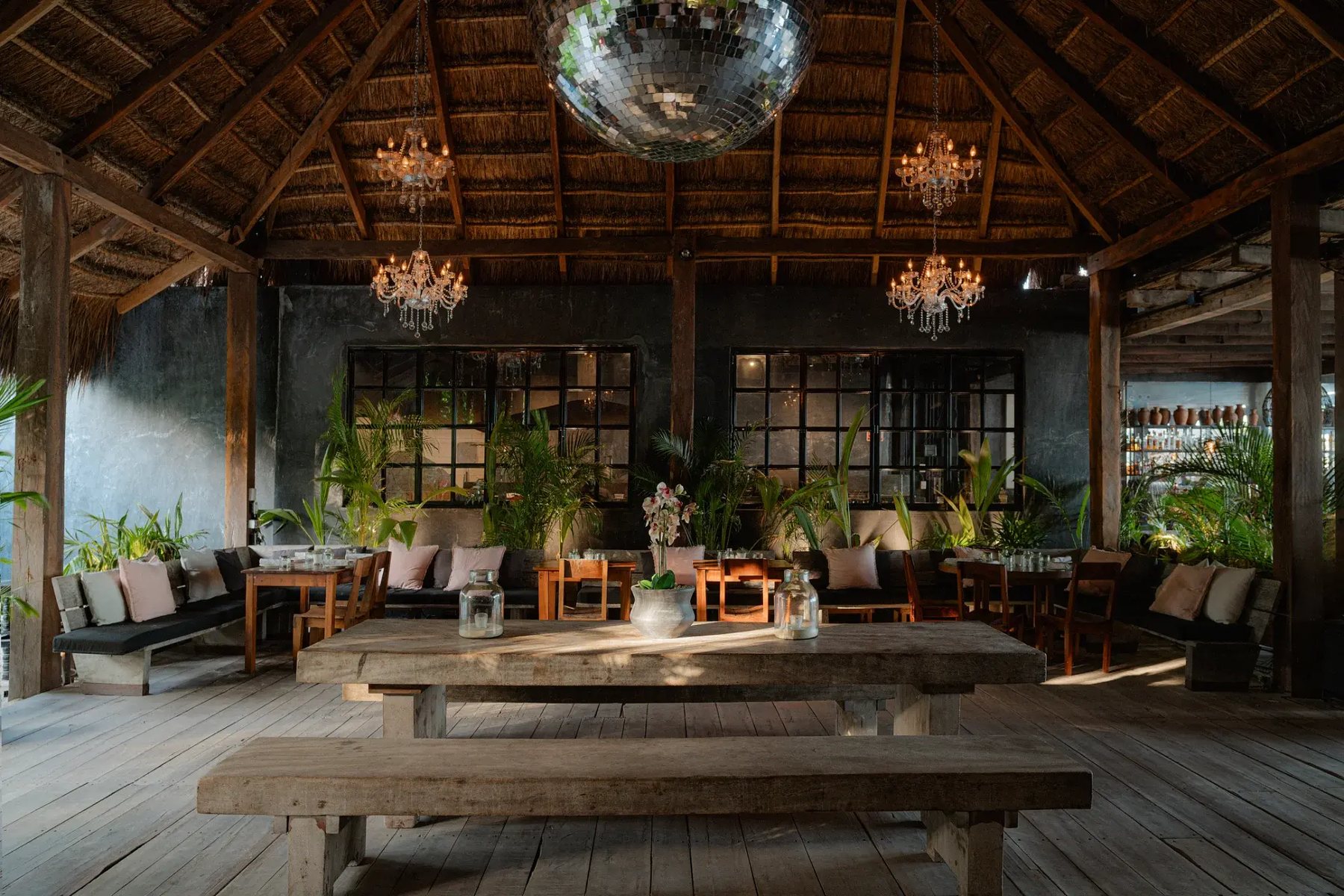 Restaurant under a palapa with chandeliers and a mirror ball