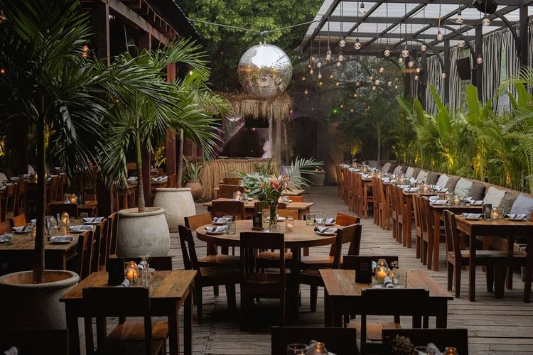 Dining area under a pergola with a mirror ball and string lights
