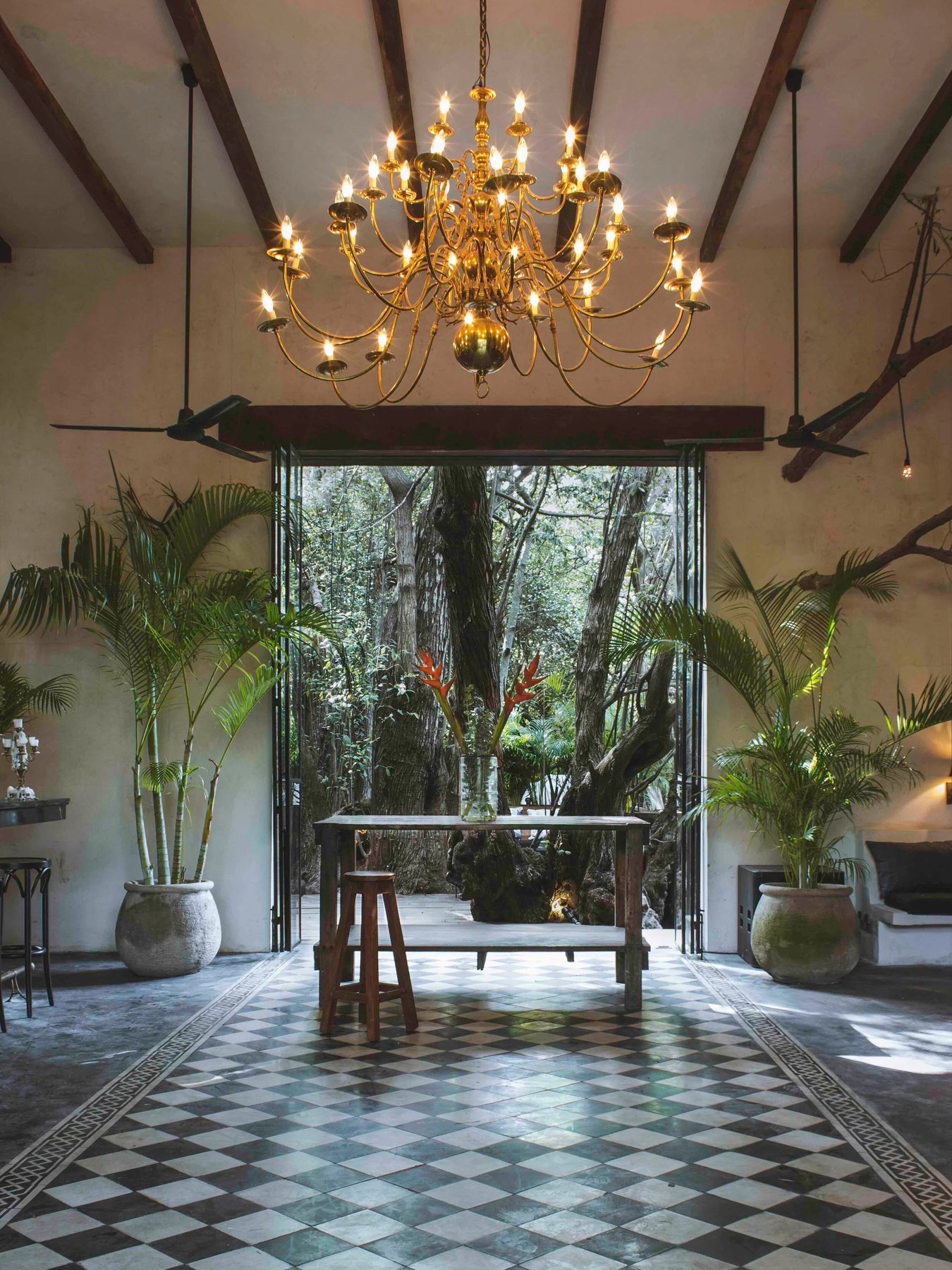 Hall with a chandelier and checkered floor open to the jungle