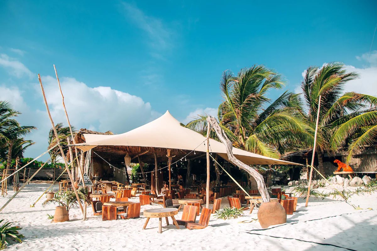Restaurant under a tent on the sand, among palms