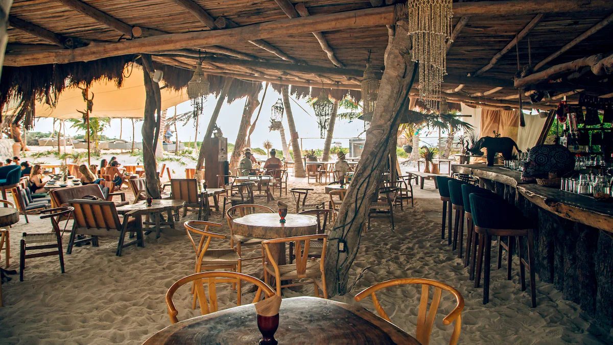 Ikal's beach restaurant with a timber bar under a palm roof, open to the sea