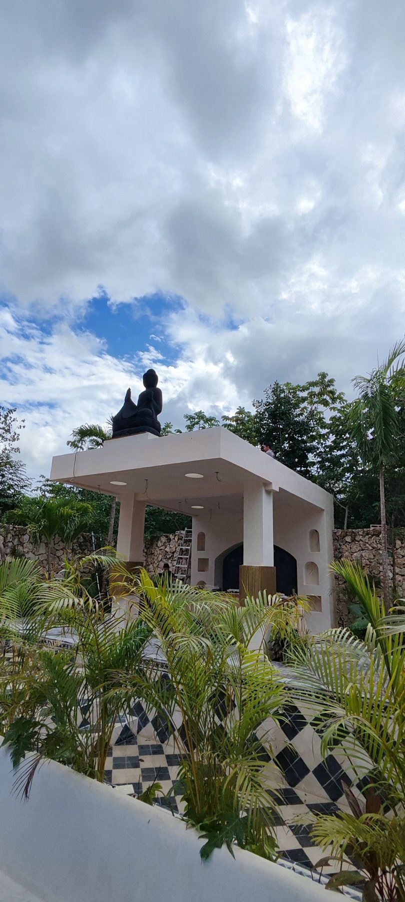 The pergola and sculpture seen through palms